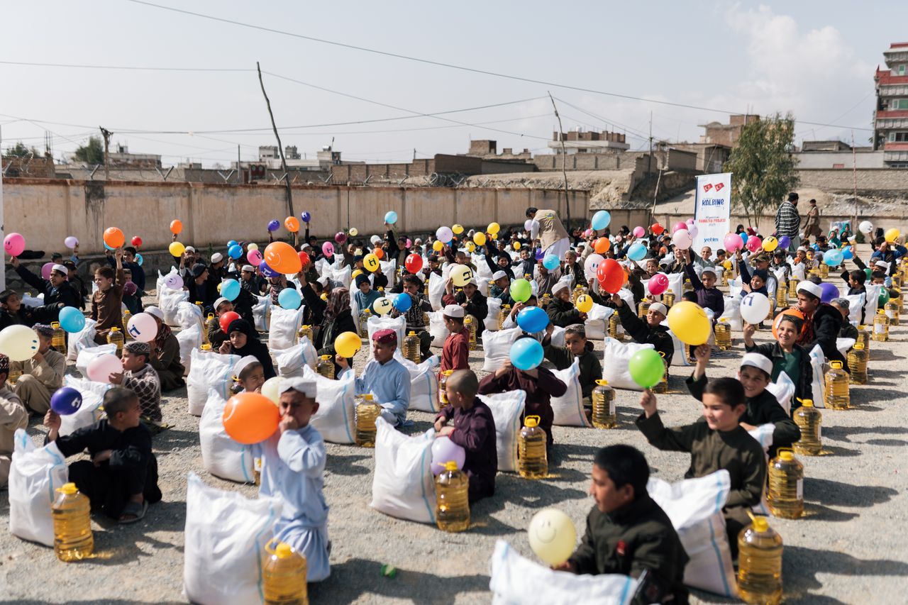 creative-02 Children gather with balloons and supplies during a daytime event in Afghanistan.
