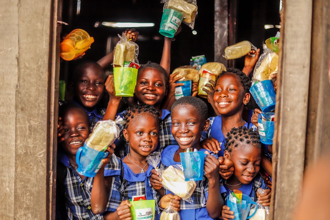 creative-03 Group of happy children holding food packages and smiling outdoors.